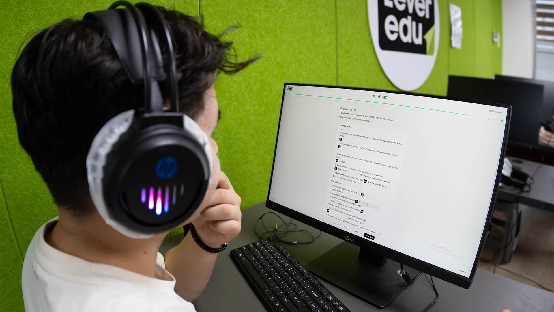 A student in headphones sitting an IELTS exam at the Lever simulation centre